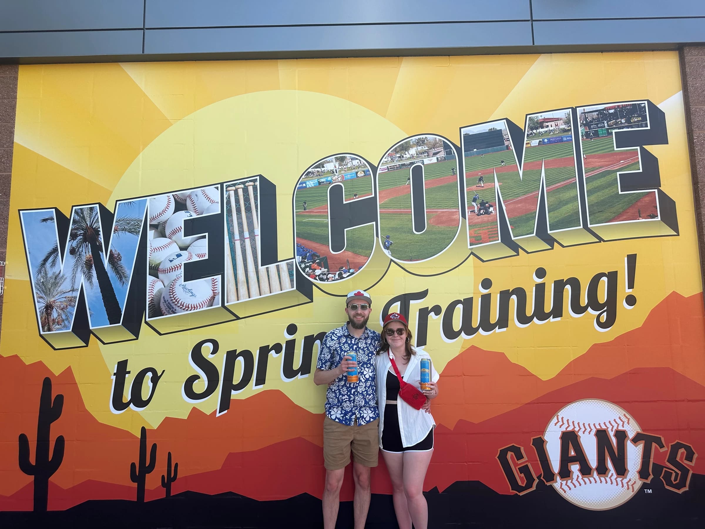 Rachel and Reid in front of a Welcome to Spring Training mural